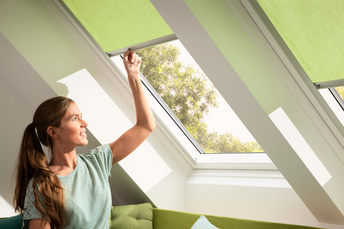 Woman adjusting green blinds on a skylight window