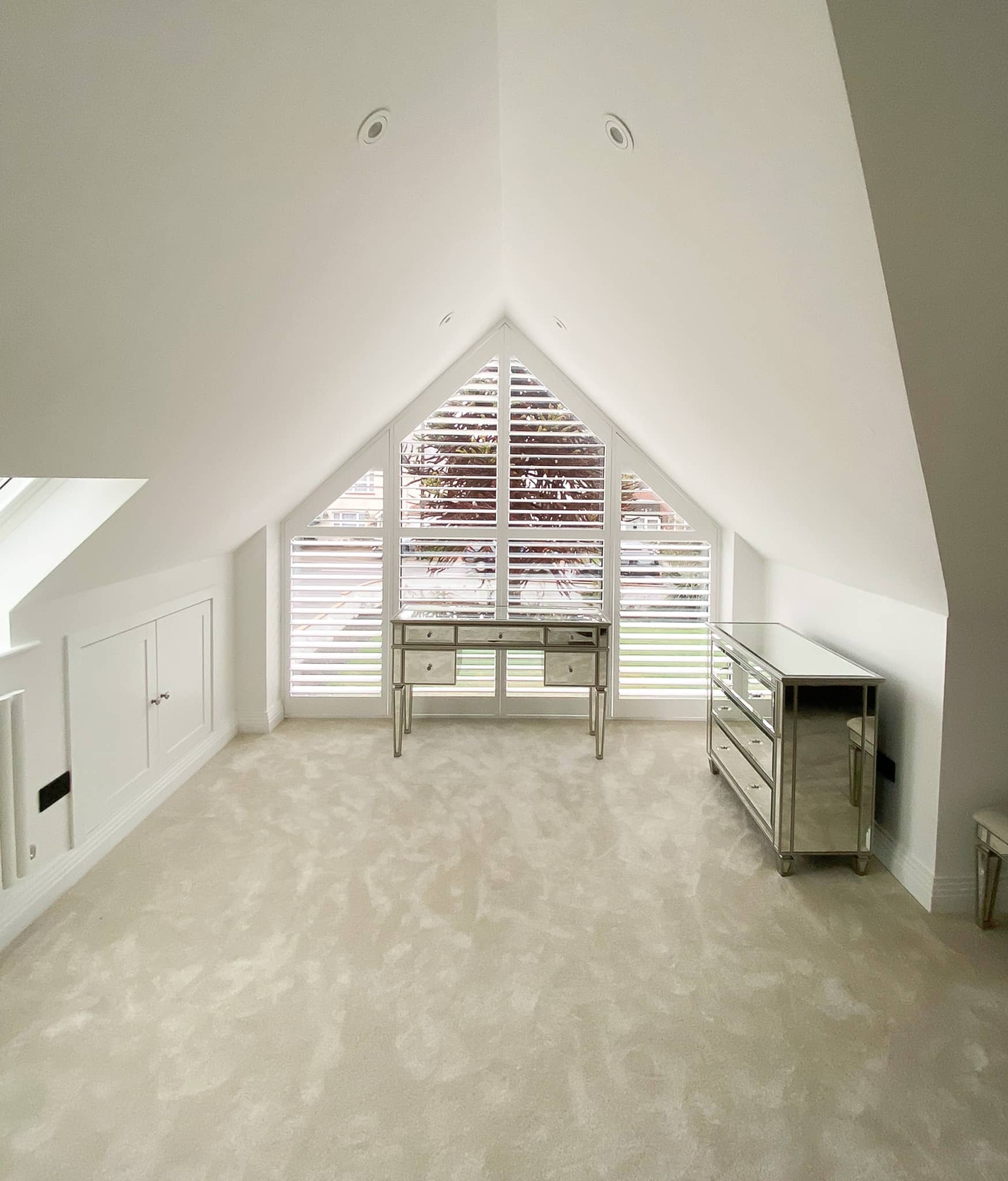 Modern attic room with white walls, a skylight, and minimal furniture.
