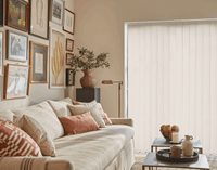 Living room with a beige sofa, decorative pillows, and a sliding glass door with vertical blinds.