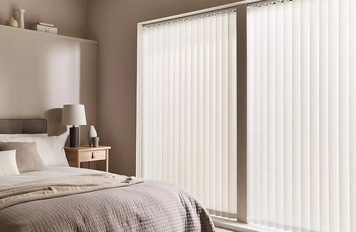 Bedroom with white vertical blinds covering a large window.